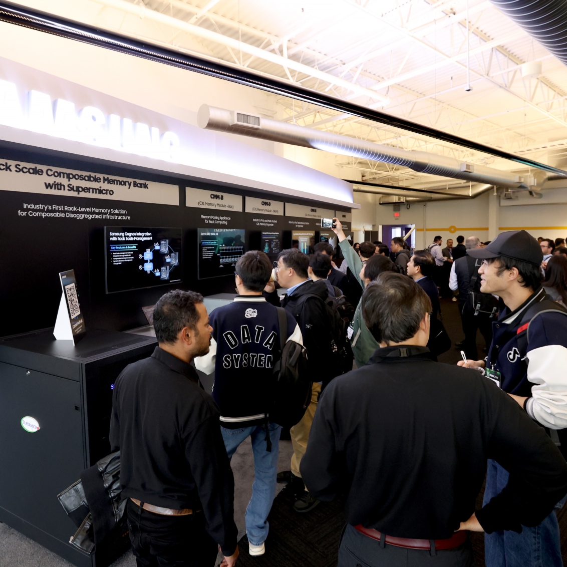 Conference attendees viewing MEMCON 2024 exhibit on Rack Scale Composable Memory Bank with a crowd gathered around.
