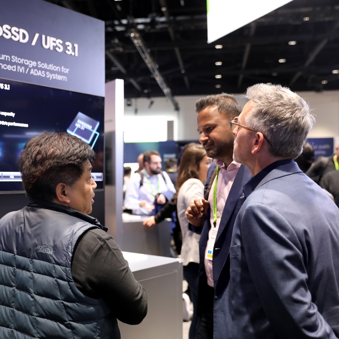 Professionals engaged in a conversation at NVIDIA GTC 2024, with a display about SSD/UFS 3.1 in the background.