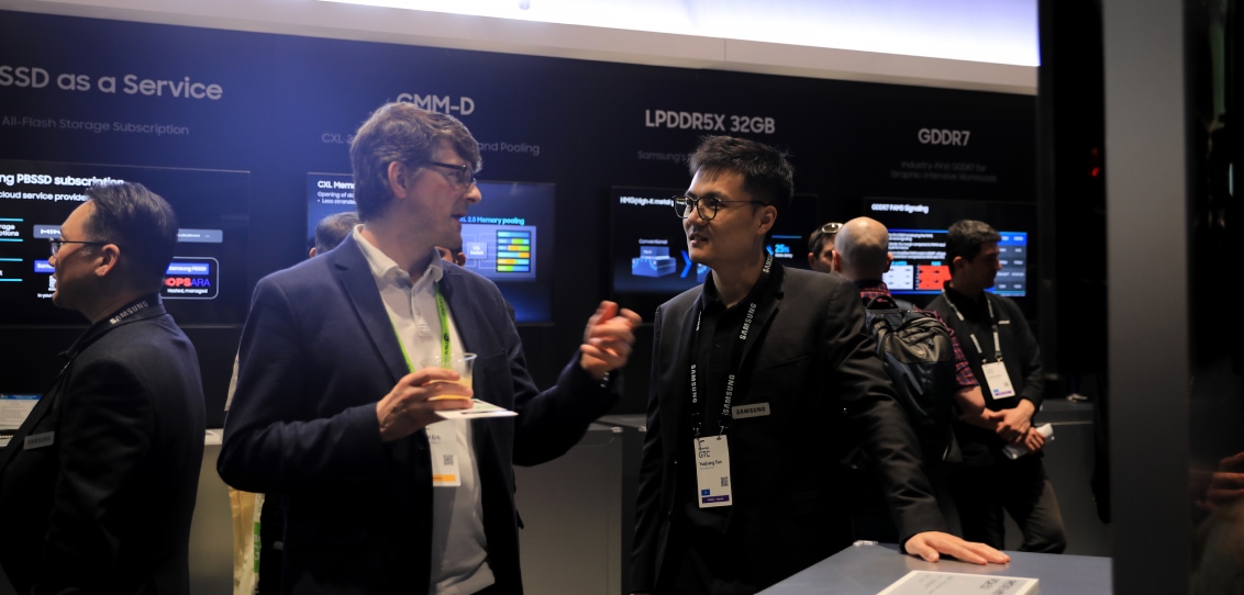 Conference attendees networking and discussing in front of a SSD as a Service exhibition display.