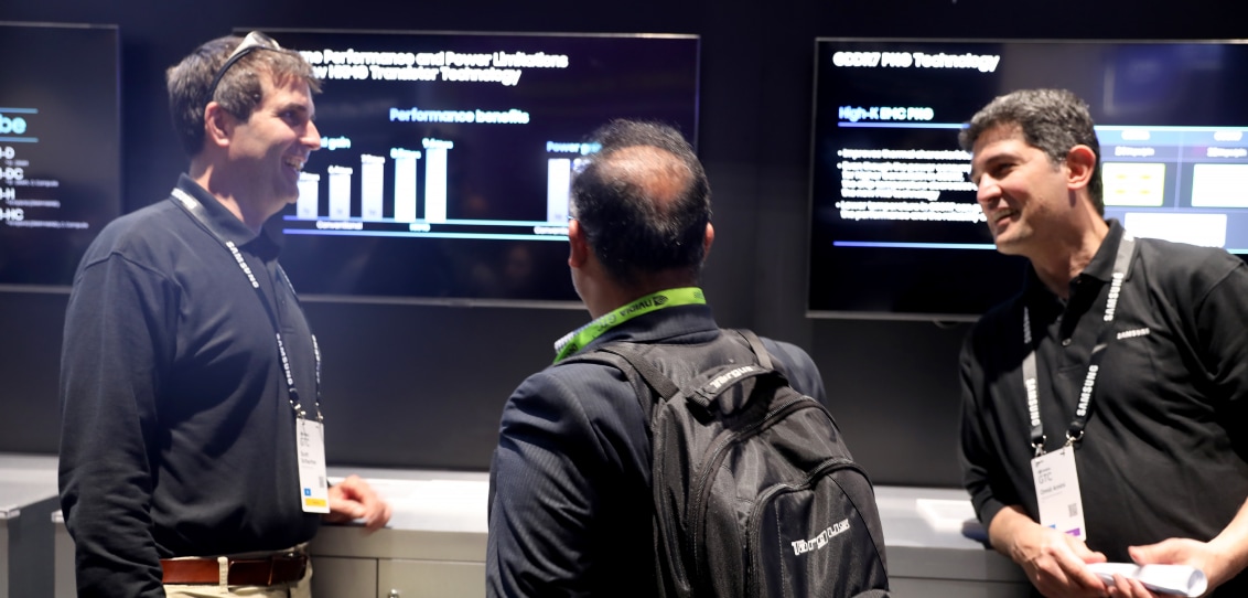 Three individuals engaged in a discussion at NVIDIA GTC 2024 with performance graphs in the background.