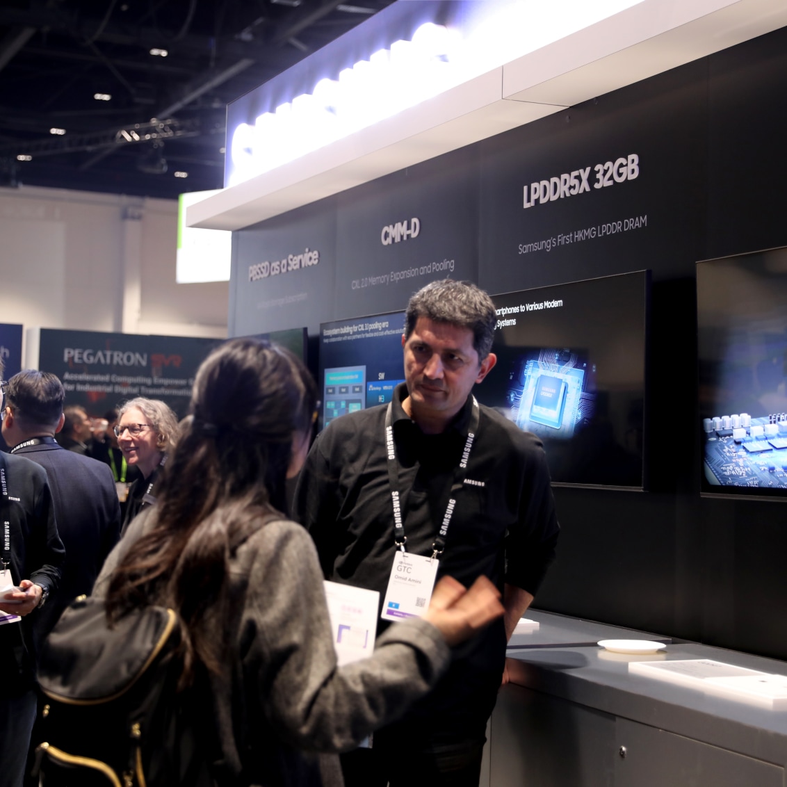 Two individuals in conversation at NVIDIA GTC 2024 with a backdrop advertising memory and storage solutions.