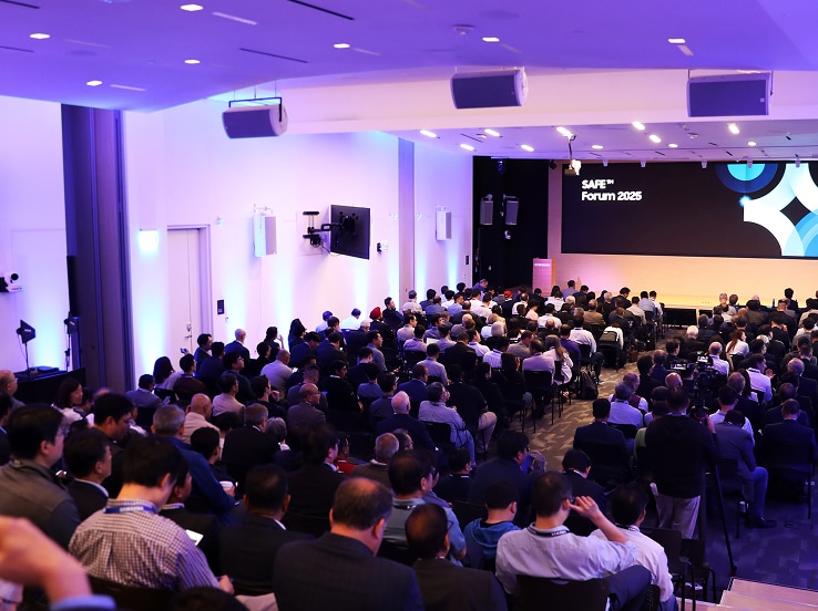 SAFE™ Forum 2025에서 현대적이고 밝은 컨퍼런스 홀을 가득 채운 참석자들이 메인 무대 발표에 집중하고 있는 모습.