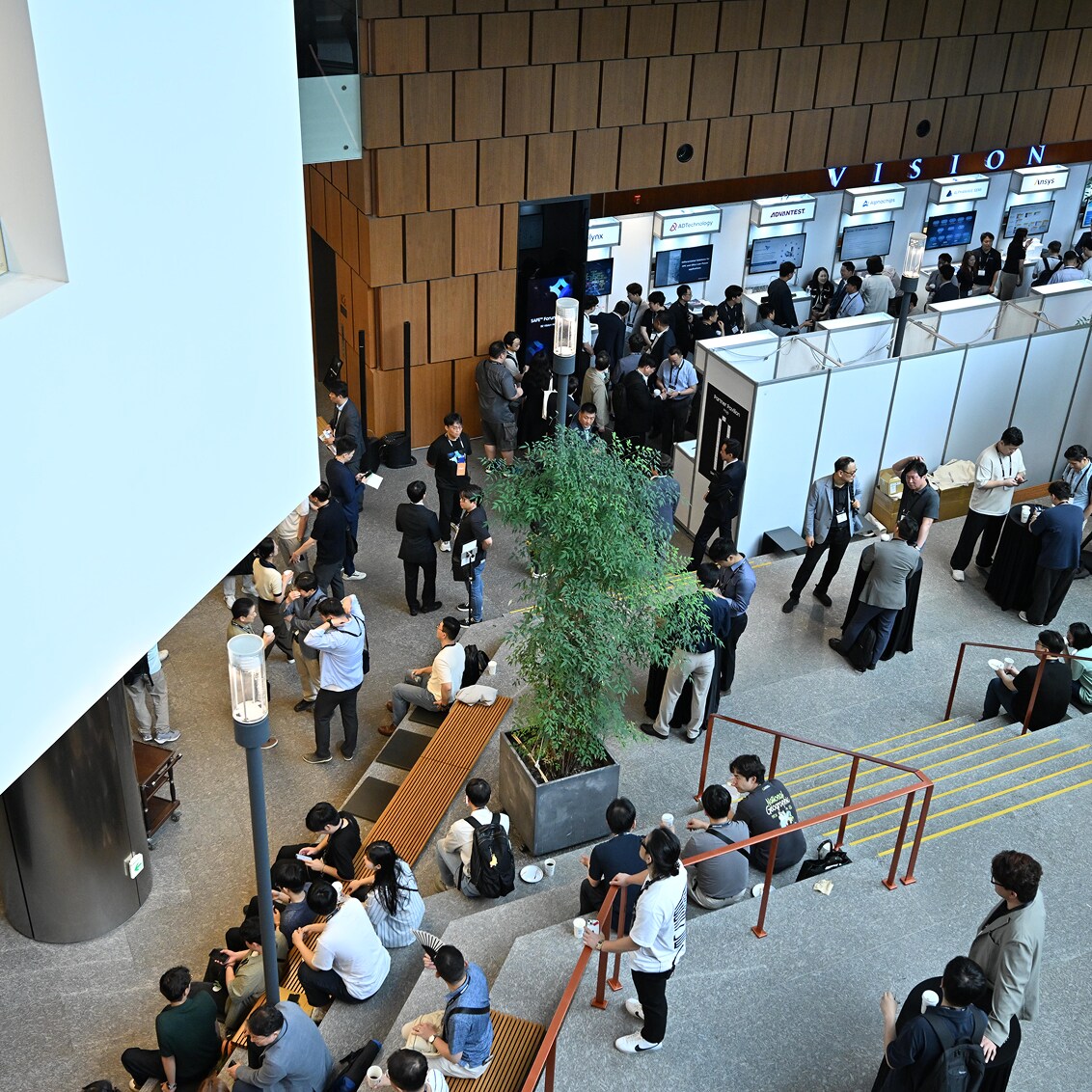 Attendees gather in a spacious lobby during SAFE™ Forum 2025, engaging in discussions and visiting exhibition booths along the walls.