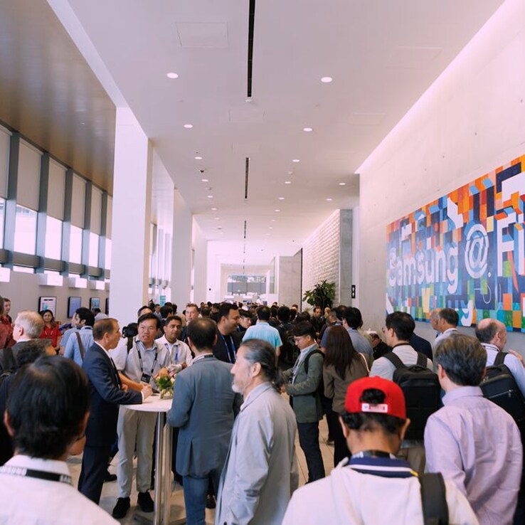 The event lobby is filled with industry professionals engaged in conversations and exchanging business cards.