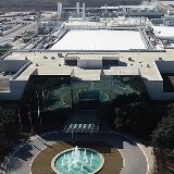 Aerial view of a semiconductor manufacturing plant with a prominent fountain and circular driveway in the foreground.