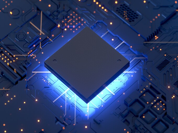 Close-up view of an electronic chip in the center of a circuit board with blue neon light and glowing connections.