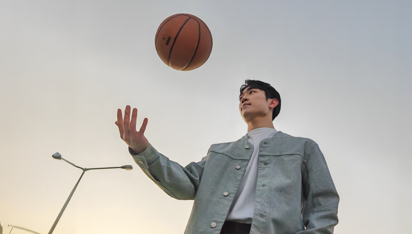 Image with the word 'Autofocus' overlaid, showing a man in a denim jacket tossing a basketball into the air against a clear sky background.
