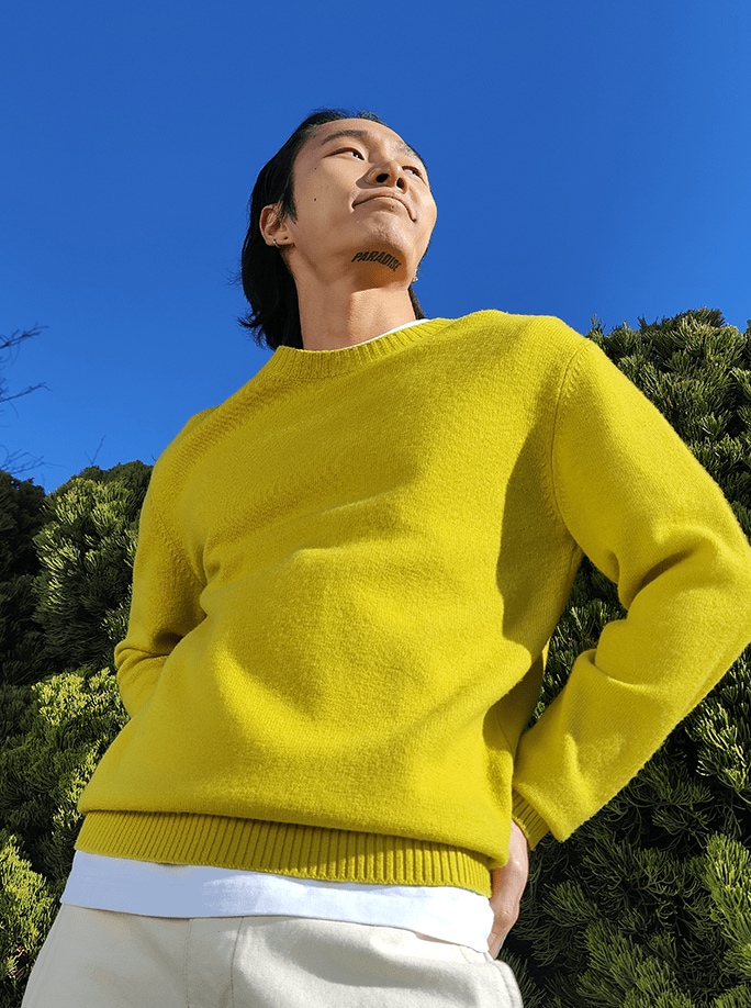 노란 스웨터를 입은 청년이 하늘을 올려다보고 있다