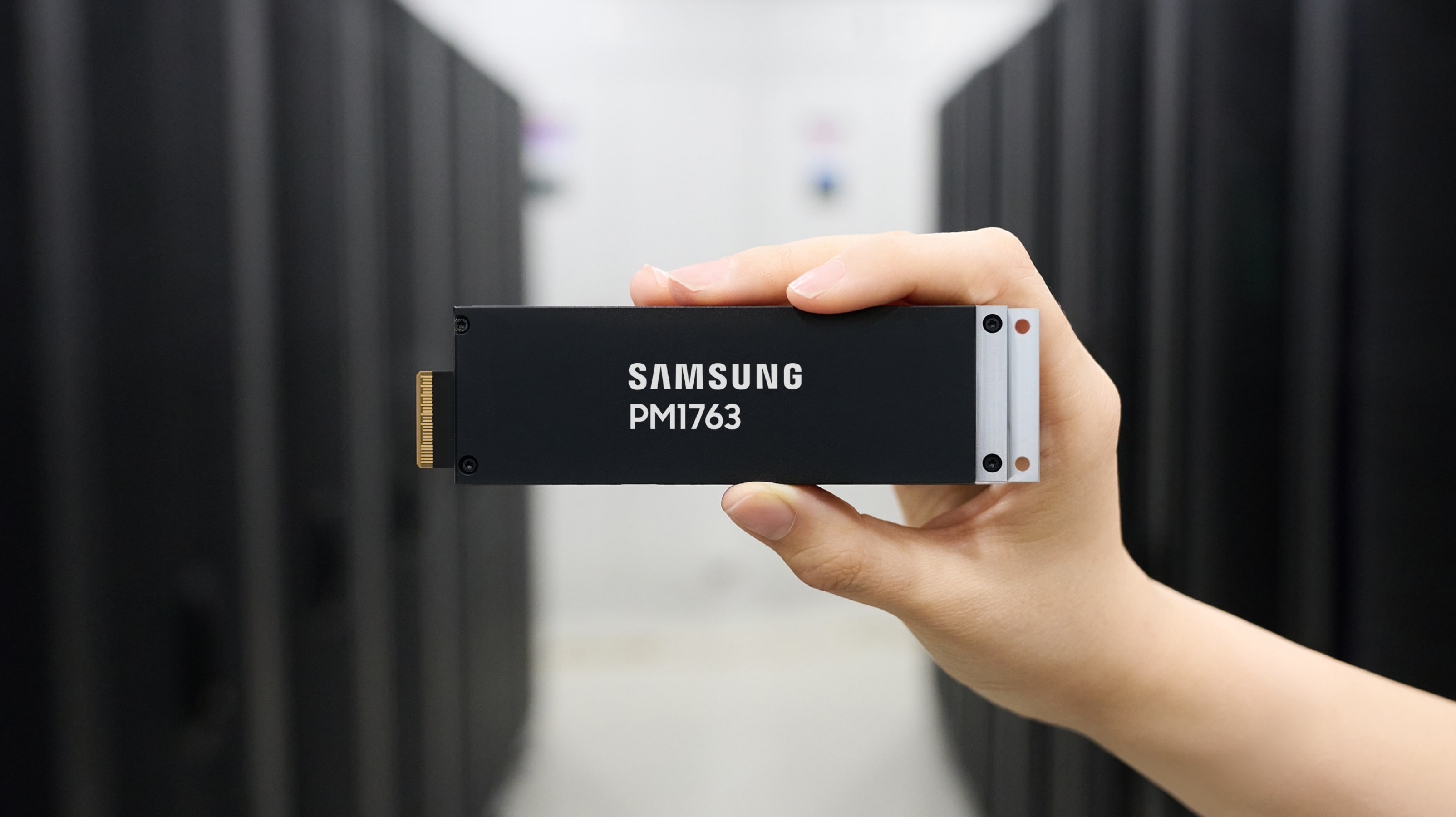 Samsung PM1763 enterprise SSD held in front of data center server racks