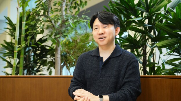 픽셀 개발 팀의 엔지니어가 실내 녹지 공간에서 미소를 지으며 인터뷰에 응하고 있는 모습.