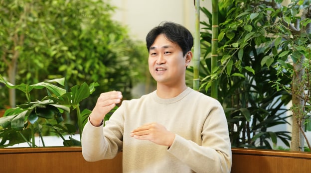 센서 솔루션 팀의 엔지니어가 실내 녹지 공간에서 손짓을 사용하며 설명하고 있는 모습.