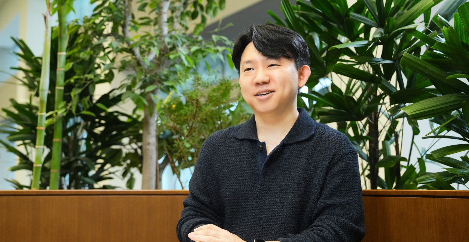 픽셀 개발 팀의 엔지니어가 실내 녹지 공간에서 미소를 지으며 인터뷰에 응하고 있는 모습.