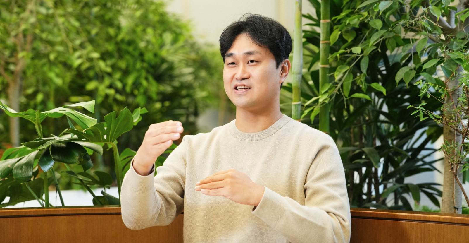 센서 솔루션 팀의 엔지니어가 실내 녹지 공간에서 손짓을 사용하며 설명하고 있는 모습.