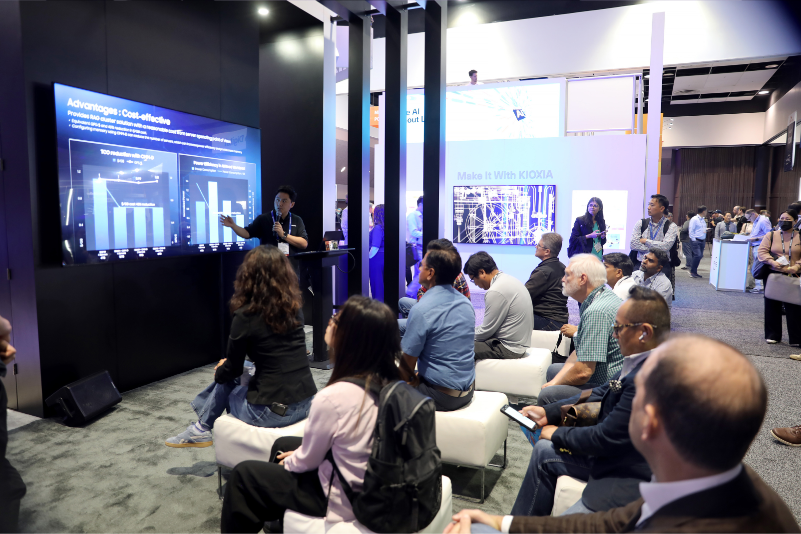 Presenter at Samsung Semiconductor booth explaining cost-effective AI memory solutions on screen to seated audience at tech conference.