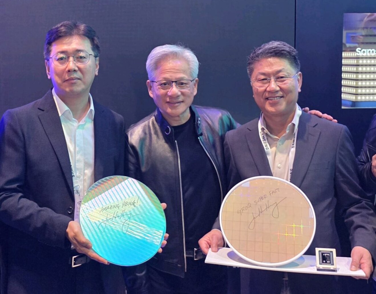 엔비디아 젠슨 황 CEO가 GTC 2026 현장에서 삼성전자 부스를 방문해 기념촬영을 하고 있는 모습 사진 좌측부터 황상준 메모리개발담당 부사장, 엔비디아 젠슨 황 CEO, 한진만 Foundry사업부장 사장 제품은 사진 좌측부터 삼성전자 HBM4 코어다이 웨이퍼와 그록(Groq) LPU 파운드리 4나노 웨이퍼 각 웨이퍼에는 ‘AMAZING HBM4’와 ‘Groq Super FAST’라는 젠슨 황 CEO의 친필 서명이 적혀있음