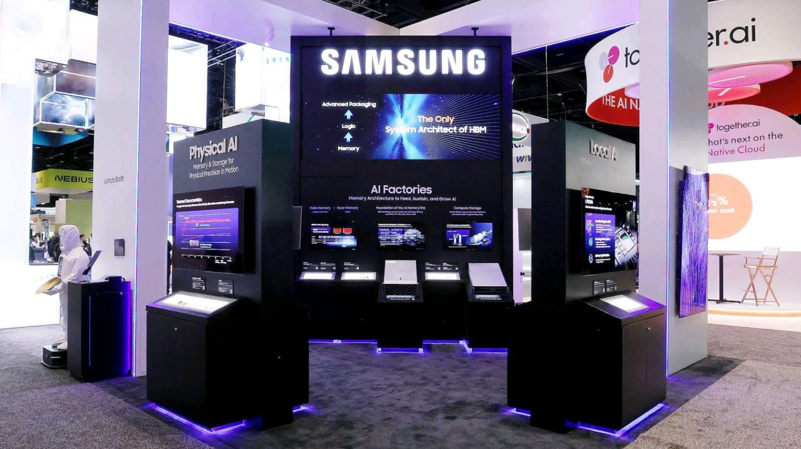 Wide view of a Samsung exhibition booth showcasing advanced semiconductor technologies, featuring display zones for "Physical AI", "AI Factories", and "Local AI", while highlighting the slogan "The Only System Architect of HBM".