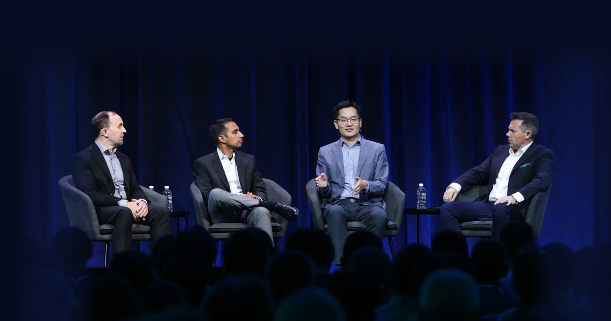 A live panel session at the 2024 OCP Global Summit, with four speakers in formal attire engaging in a conversation.