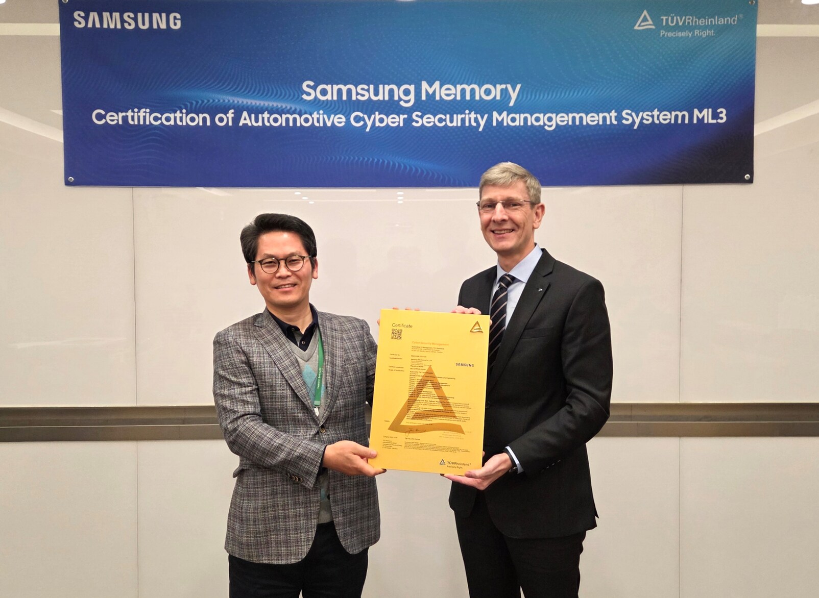 Soonjae Won, EVP of Samsung Electronics’ Memory Business, and Frank Juettner, CEO of TÜV Rheinland Korea, stand together in front of a blue Samsung Memory banner while holding a yellow CSMS ML3 certification plaque during the handover ceremony.