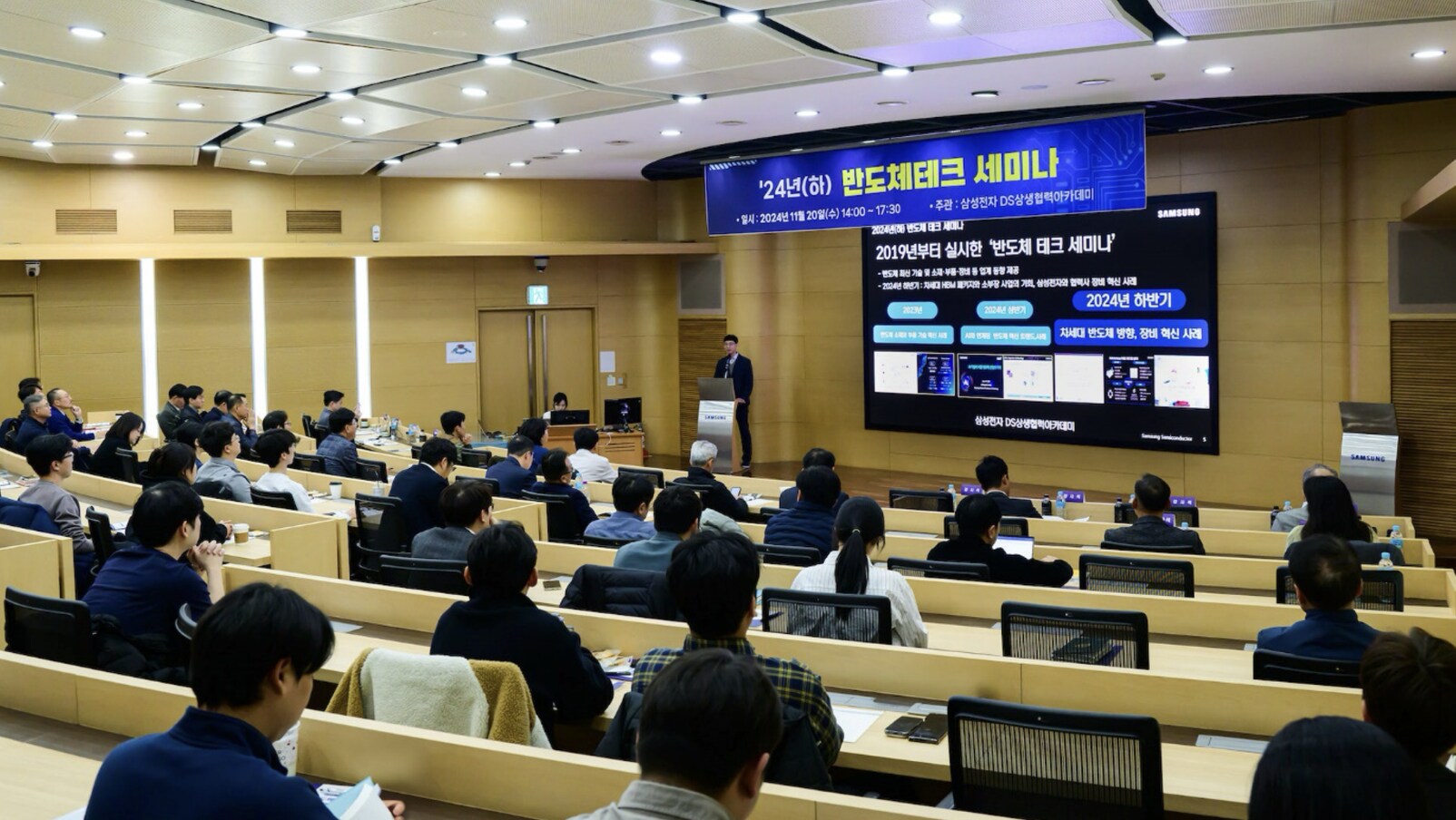 A wide view of the 2024 Semiconductor Tech Seminar, with attendees in a bright lecture hall and a presenter on stage.