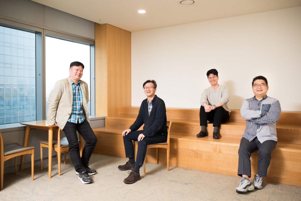 왼쪽부터 8K TV 속 IC 개발에 참여한 삼성전자 김상덕, 성한수, 임정현, 송용주 씨가 원목 의자에 앉아 환하게 웃고 있다.