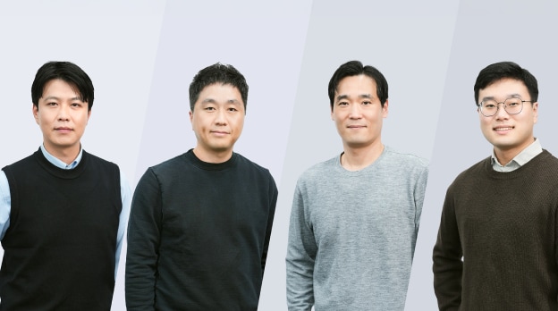 남성 4명이 함께 서 있는 단체 사진.