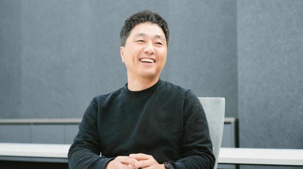 회의실에서 책상 앞에 앉아 미소를 짓는 남성.