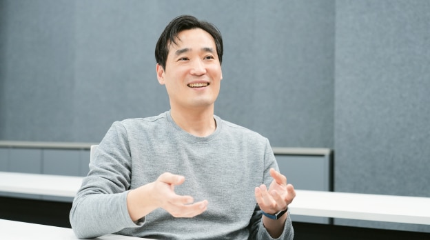 회의실에서 책상 앞에 앉아 손짓하는 남성.