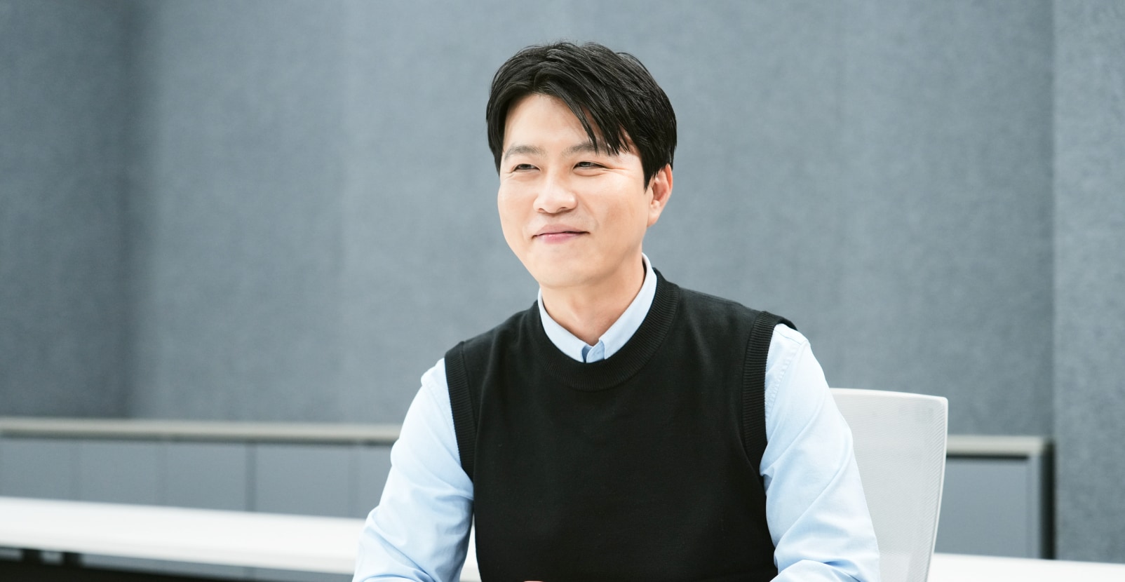 회의실에서 책상 앞에 앉아 있는 남성.