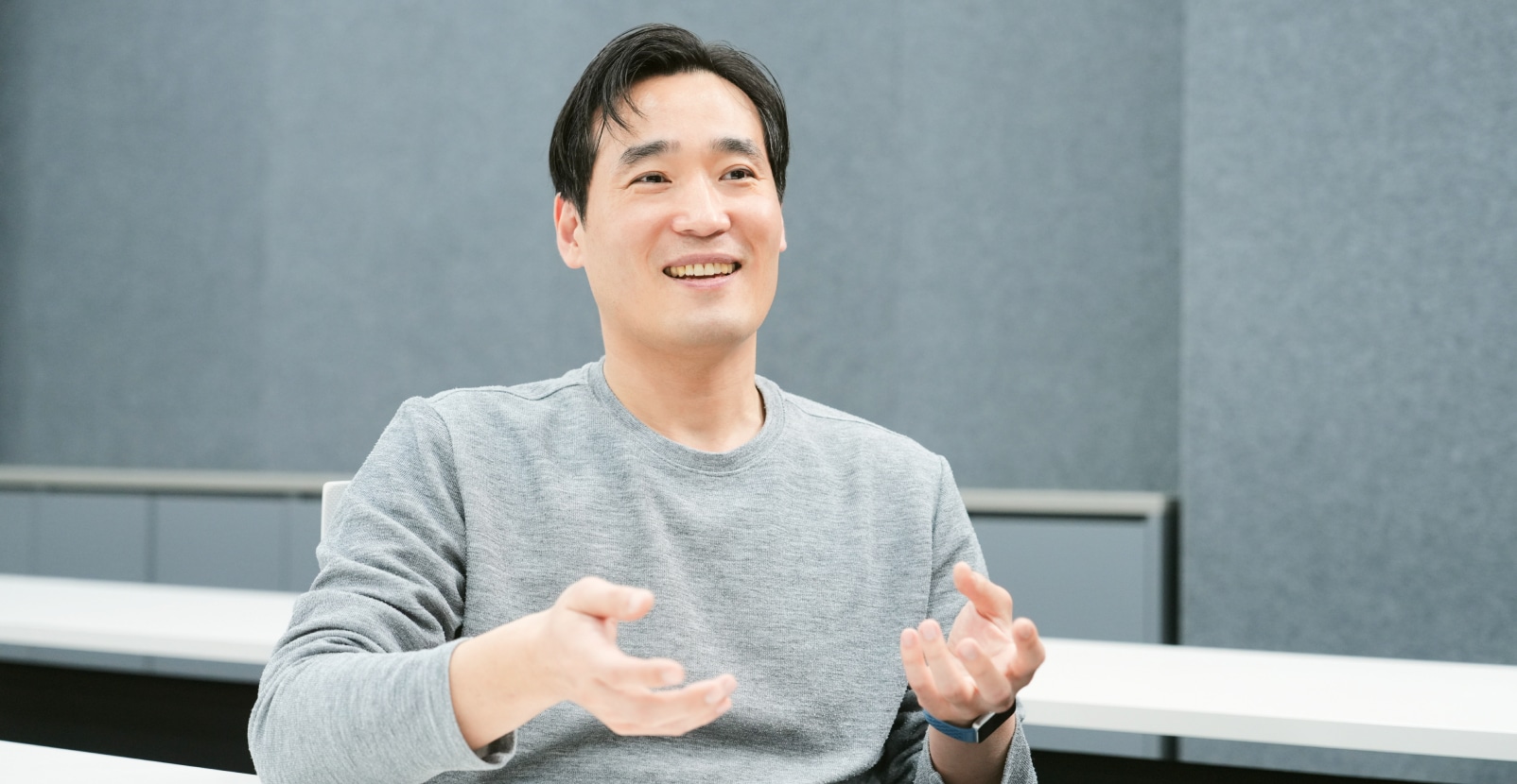 회의실에서 책상 앞에 앉아 손짓하는 남성.