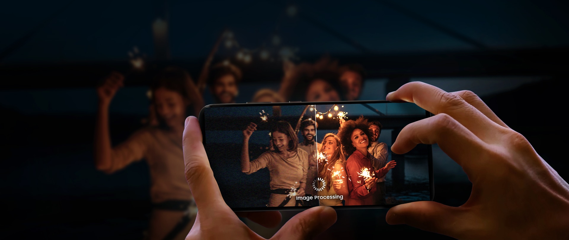 A person holds a smartphone capturing a group of people celebrating at night, emphasizing the phone's low-light photography and image processing capabilities.