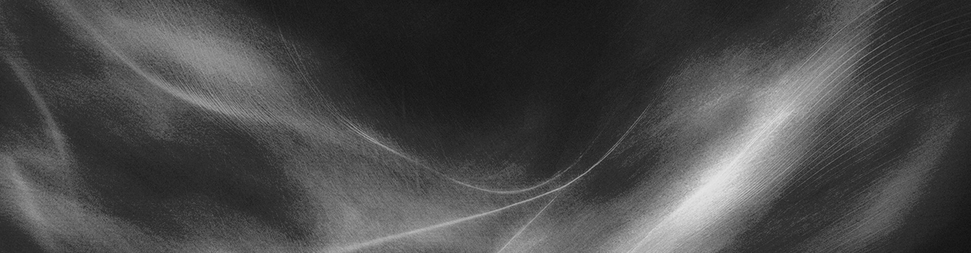 柔らかくスモーキーな波のテクスチャと、中央付近で交差する微妙な斜めの光の筋が入った、幅広い抽象的な黒とグレーの背景。