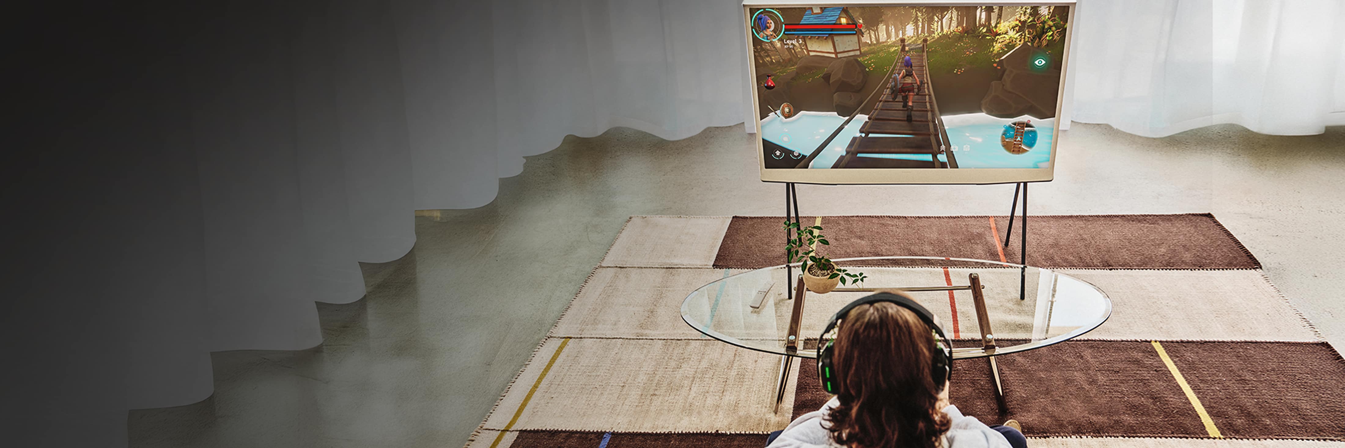 A man is sitting and playing a game on his console while watching the TV screen.