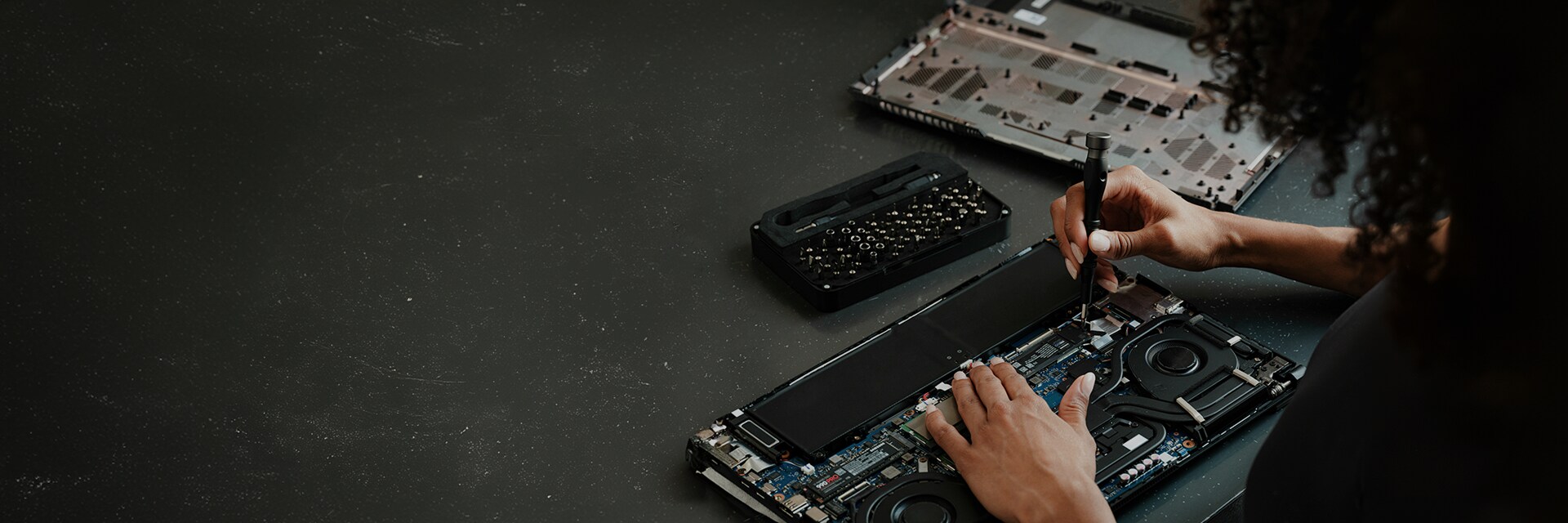 A person upgrading an SSD on a laptop, with various computer components spread out on a table