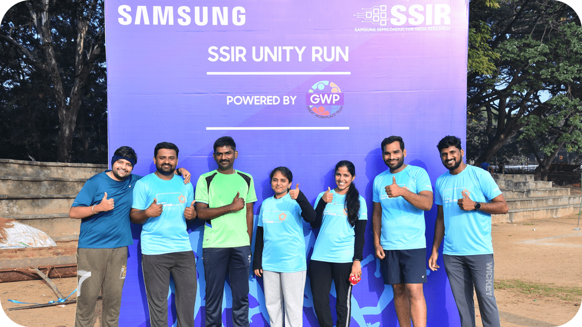 A group of participants posing in front of a Samsung SSIR Unity Run banner, all smiling and giving thumbs up in athletic attire.