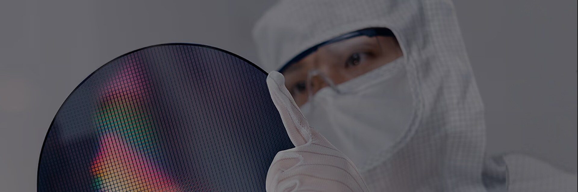 クリーンルームで防塵服と手袋を着用したエンジニアが半導体ウエハー表面を確認する様子