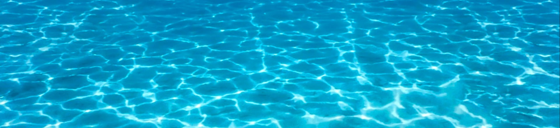 澄んだ青い水の上に太陽の光が反射して波の形を作る場面です。