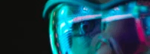 A person wearing safety goggles looks diagonally to the left and the image is enlarged focusing on the left eye.