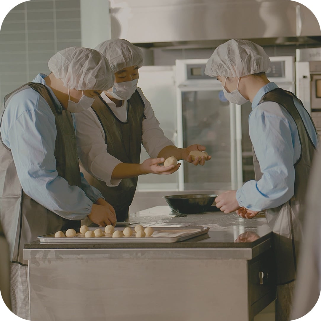 图为三名员工在星林工作机构制作面包（产品）