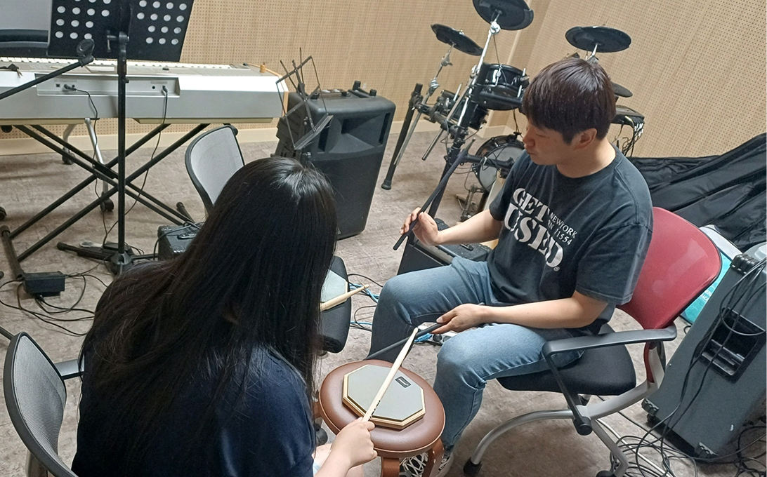 임직원이 학생들에게 드럼을 가치는 모습