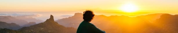 Rear view of a person looking at a sunset.