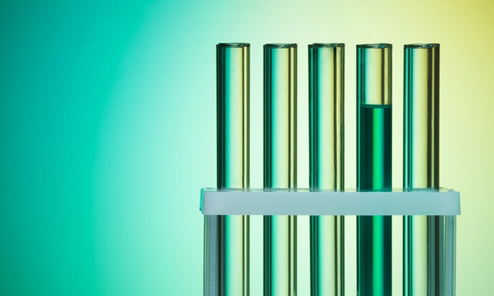 Five test tubes seen from the front with the fourth one seen full of a green liquid.