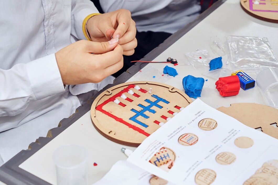A student wearing a school uniform is assembling a semiconductor science classroom kit.