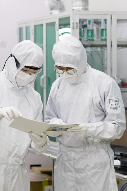 Two people in protective gear looking at documents.